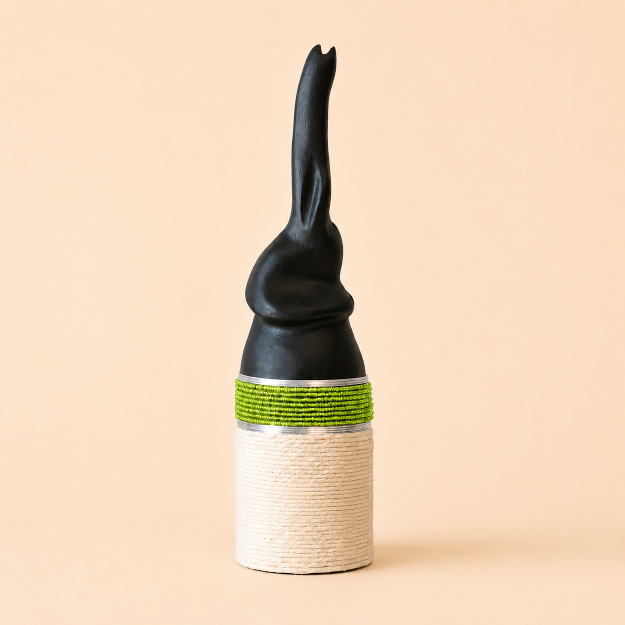 Decorative carved elephant with black top, green band, and white base on a beige background