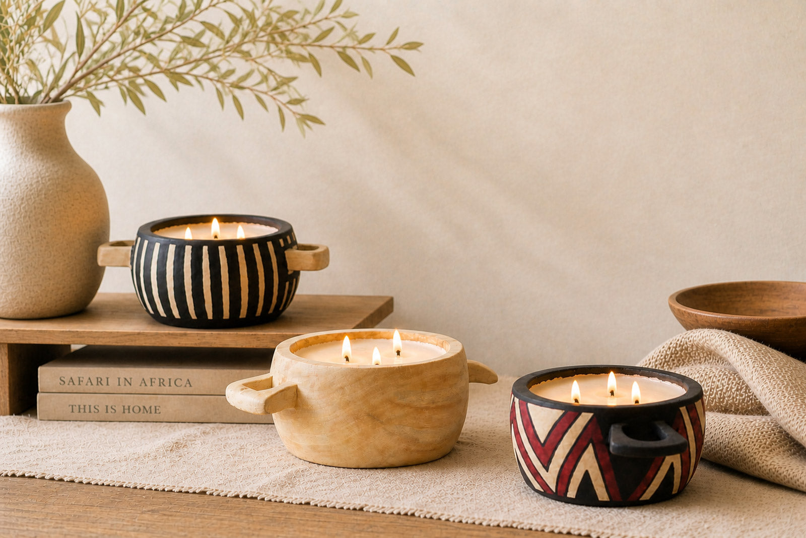 Decorative candles in unique holders on a wooden surface with a neutral background