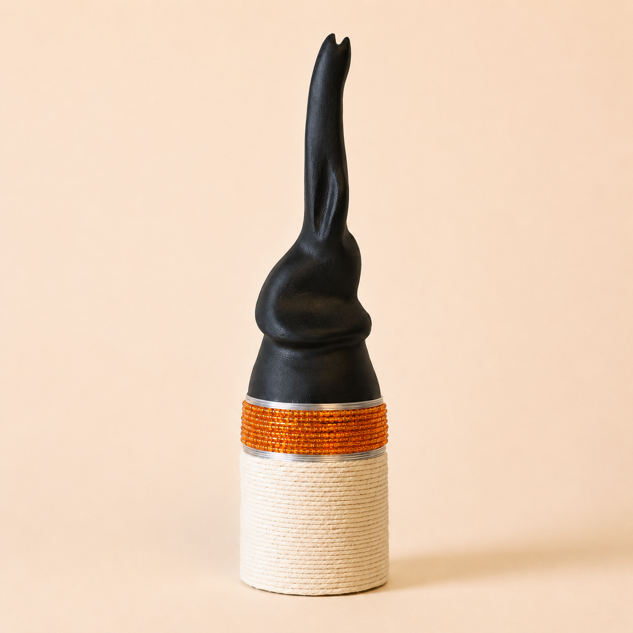 Black abstract carved elephant with orange and white base on a beige background