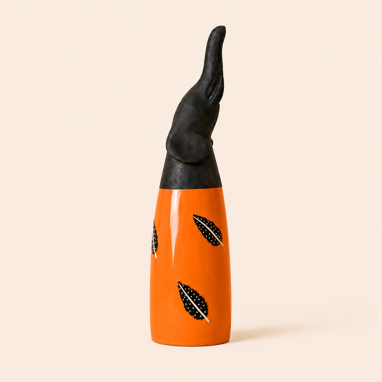 Black and orange african carved elephant with feather designs on a beige background