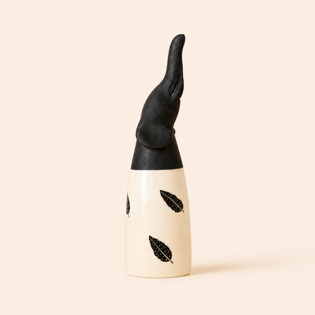 Black and white African carved elephant with feather designs on a beige background