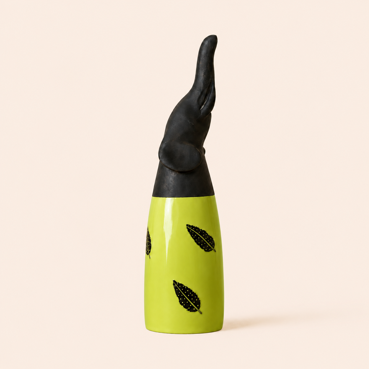 Black and green african carved elephant with feather patterns on a beige background