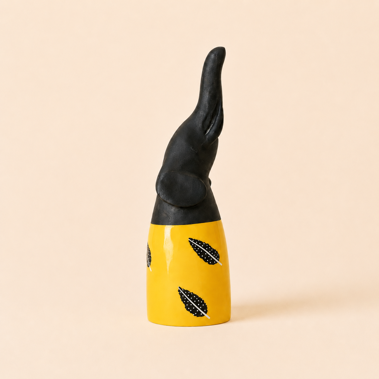 Black and yellow African carved elephant with Feather patterns on a beige background