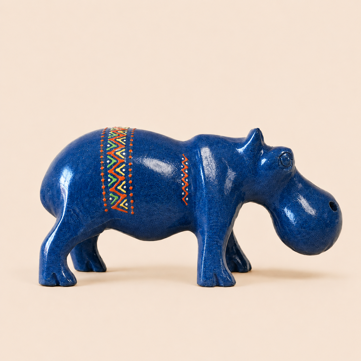Blue hippo figurine with decorative patterns on a beige background