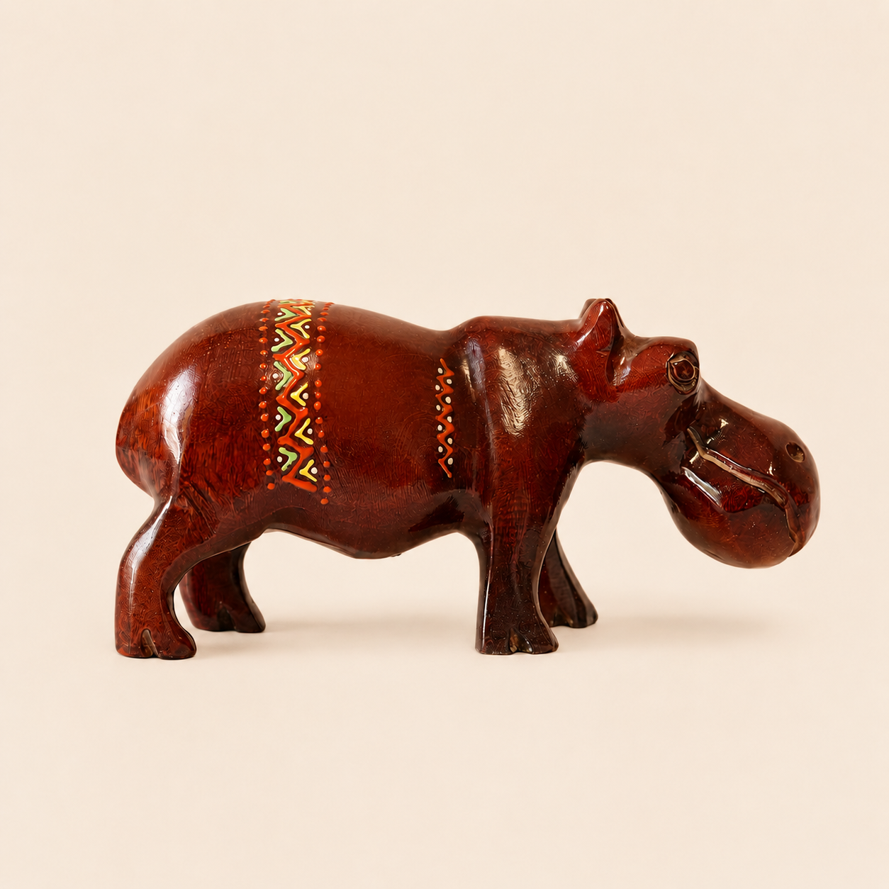 Decorative burgundy hippo figurine with tribal patterns on a beige background