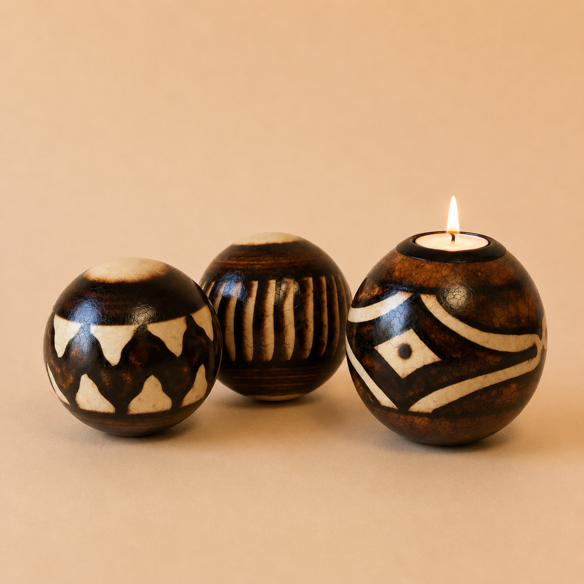 Patterned Monkey Balls & Tlite with burnt designs on the natural wood set on a beige background.