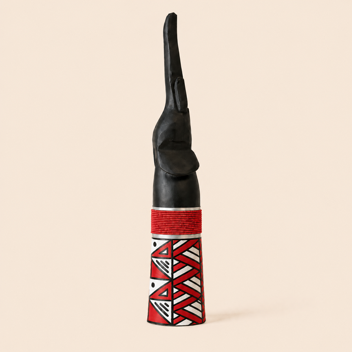 Wood carved Goodluck elephant with red beads and red Ndebele patterns on a beige background