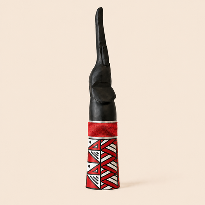 Wood carved Goodluck elephant with red beads and red Ndebele patterns on a beige background